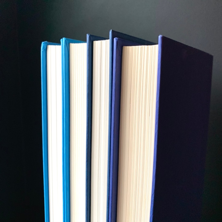 Four books in shades of blue against a black background.